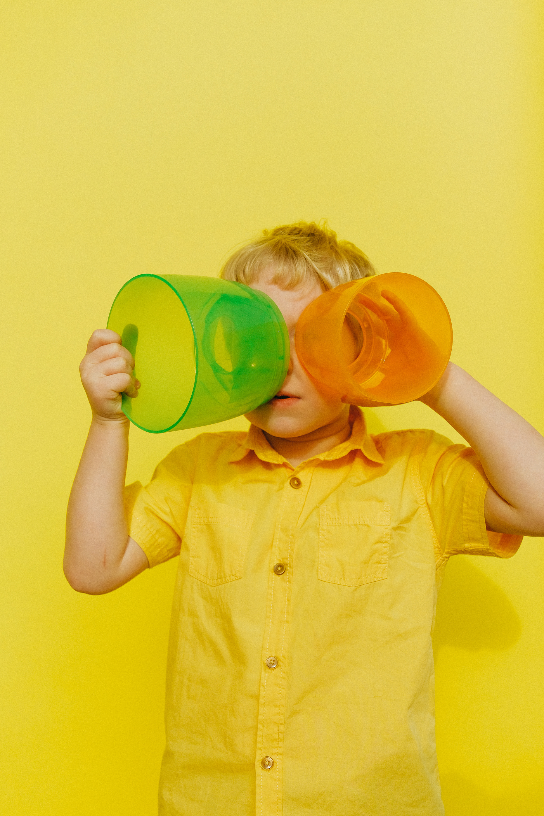 Boy in Yellow Button Up Shirt Holding Yellow and Green Plastic Containers